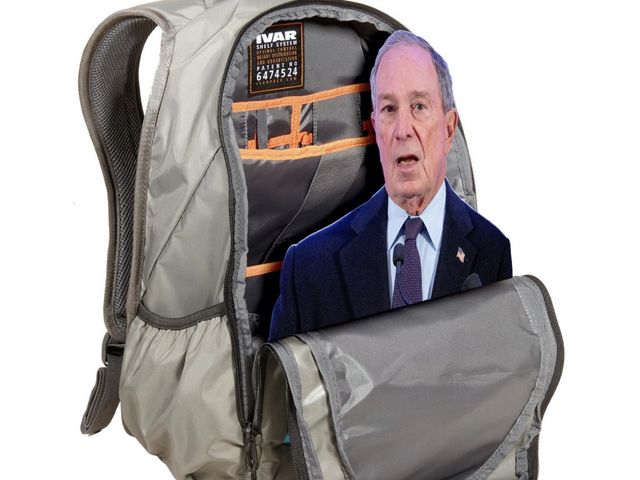 A tan backpack, half open,
revealing a cutout of Michael Bloomberg